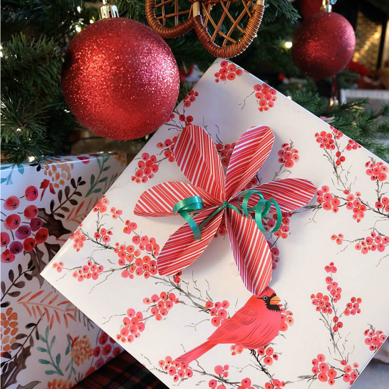 Skip the store bought bows and DIY them instead! Learn How To Make Super Simple DIY Poinsettia Bows For Gift Wrapping. They are so easy and perfect for wrapping Christmas gifts!
