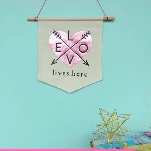 Canvas Wall Banners are so hot right now! Learn how to make a DIY Canvas Wall Banner in just 20 minutes with this easy sewing tutorial! Includes a free Cricut Cut File for making this Love Lives Here Banner on the Cricut Maker or Cricut Explore! Perfect for decorating a family photo wall or as a front door wreath decoration for Valentines Day! #DIY #CricutMade #CricutMaker #Craft #Decor