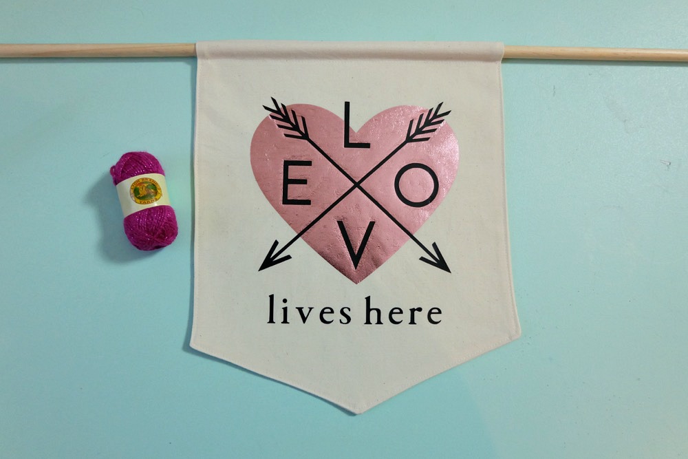 Canvas Wall Banners are so hot right now! Learn how to make a DIY Canvas Wall Banner in just 20 minutes with this easy sewing tutorial! Includes a free Cricut Cut File for making this Love Lives Here Banner on the Cricut Maker or Cricut Explore! Perfect for decorating a family photo wall or as a front door wreath decoration for Valentines Day! #DIY #CricutMade #CricutMaker #Craft #Decor