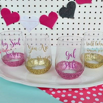 Celebrate Galentine's Day (aka Valentine's Day for with your BFF's) with these super cute DIY Glitter Wine Glasses. This post shares word art to make 6 different glasses along with an easy step by step tutorial with photos for how to make this project. This would be a great crafternoon project with friends! Use your Cricut to cut the word art. #CricutMade #Crafts #Galentine #DIY #Glitter #Valentine