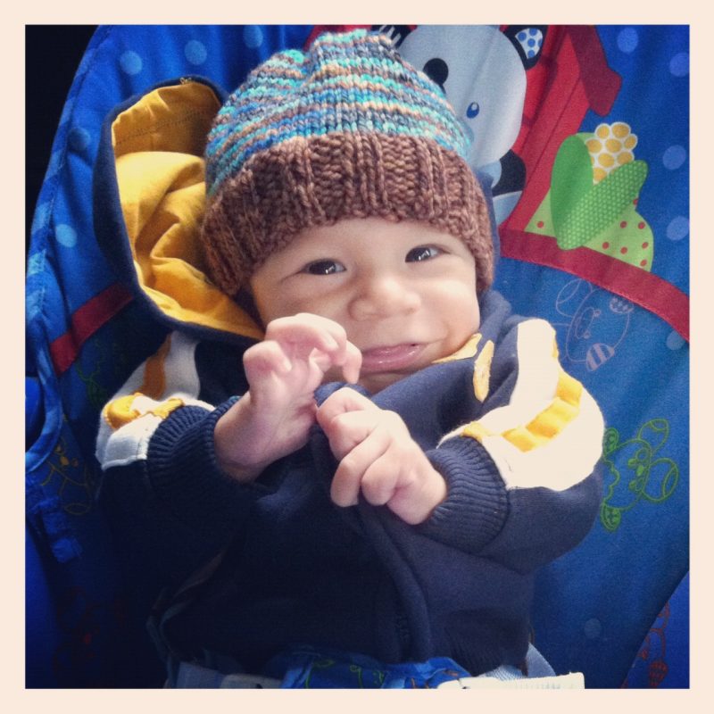 Cute little boy with a big smile and a knitted hat on his head. 