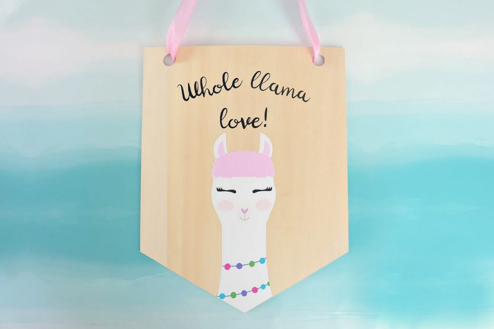 Learn how to cut basswood with your Cricut Maker and make this adorable DIY Llama Wood Wall Hanging featuring acute Print and Cut llama and the quote Whole Llama Love. This craft would make a sweet handmade gift and would be perfect for decorating a girl's bedroom or as a fun front door decoration. Another amazing Cricut Project from Hello Creative Family. #CricutProject #handmade #llama #girlsroom