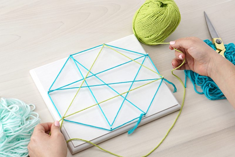 We're combining two of our favorite things-- air plants and string art to create one amazing project! Check out our DIY Air Plant String Art Tutorial to learn how to make this awesome home decor piece that's easy and low maintenance to care for. These would make great handmade housewarming gifts, graduation gifts, teacher gifts, wedding shower gifts and more! #AirPlants #StringArt #DIY #Crafts