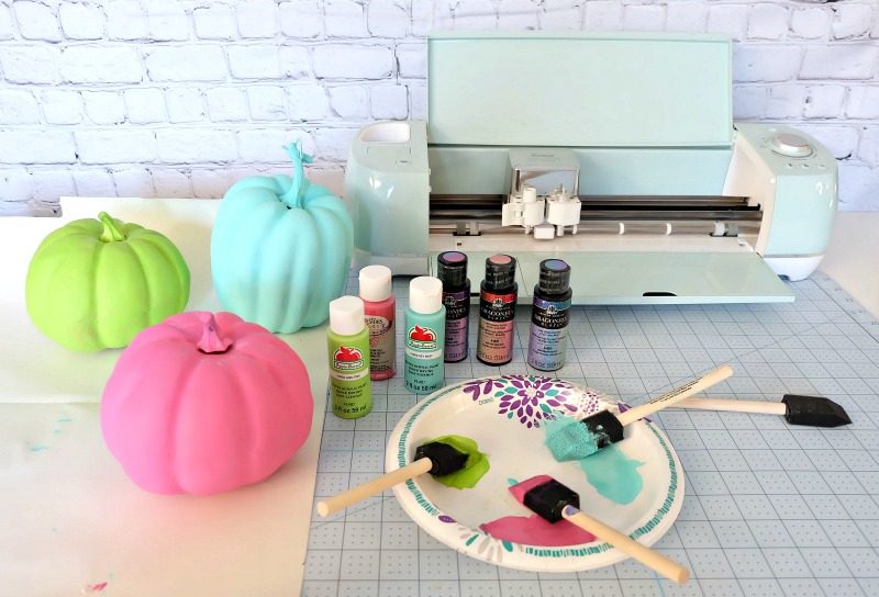 Add some flare to dollar store craft pumpkins with our easy painted pumpkins tutorial! With a bit of paint and some vinyl decals you cut with your Cricut this project makes a fun family friendly Halloween craft! #DIYHalloween #CricutCreated #Cricut #CraftPumpkins