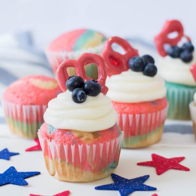 Celebrate the Fourth of July with this Patriotic Cupcakes Recipe! With red, white and blue swirls, buttercream frosting, hand dipped candy coated pretzels and blueberries, this is a fun Fourth of July Cupcake decorating idea! Great for other patriotic holidays too! Who doesnt love red, white and blue food ideas! #Cupcakes #FourthOfJuly #Patriotic #Baking #CupcakeDecorating #Recipe #CupcakeRecipe #RedWhiteAndBlue #PatrioticFood