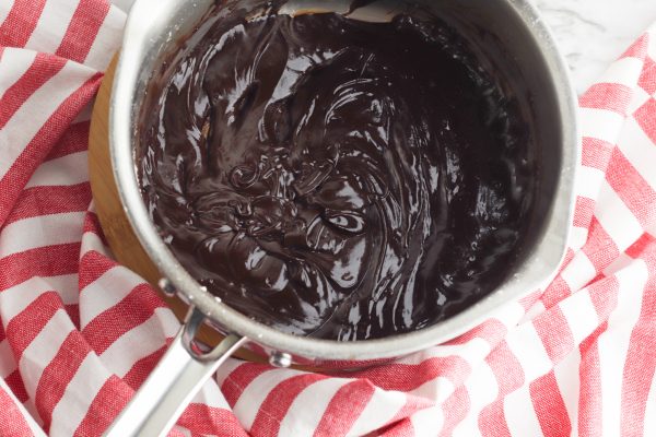 When the cake is cool, prepare the topping by melting the butter and cocoa powder in a small saucepan, stirring constantly. When the butter is melted and the chocolate is well combined, remove from heat and add the powdered sugar, peppermint extract, and one tablespoon of hot water. Stir to combine. Add more water as needed until desired consistency is reached.