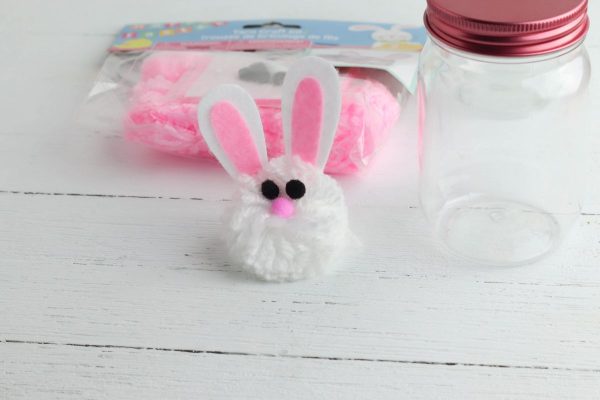 Glue the bunny ears to the top of the yarn pom pom.