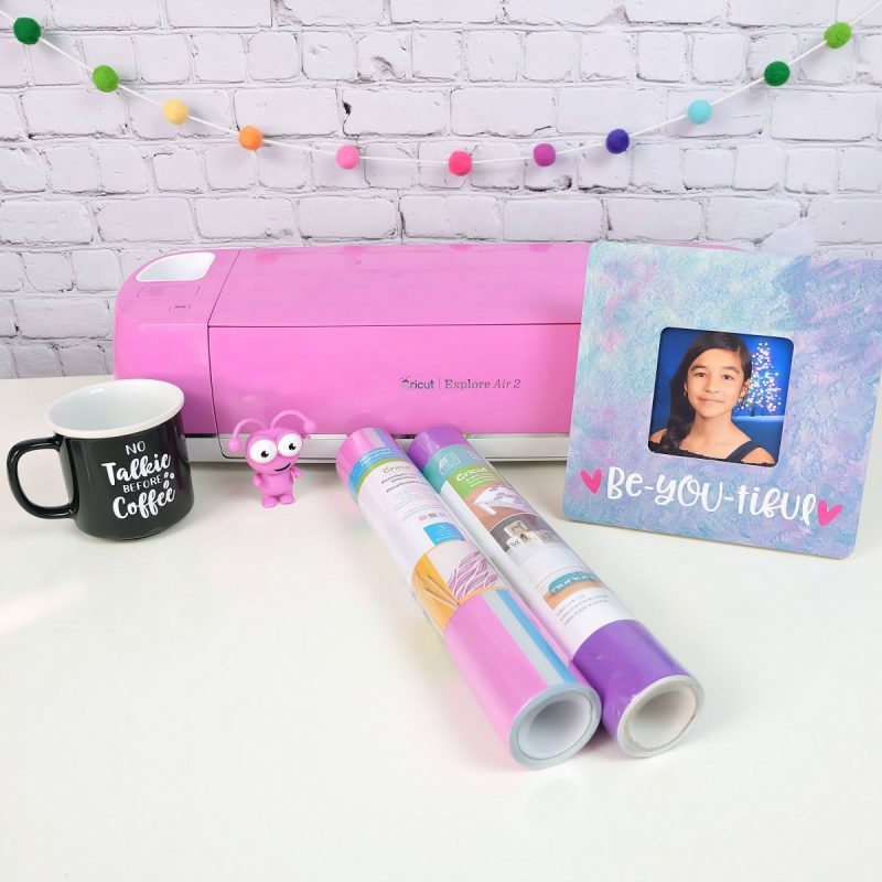Pink Cricut Explore Air 2 with vinyl and craft projects.