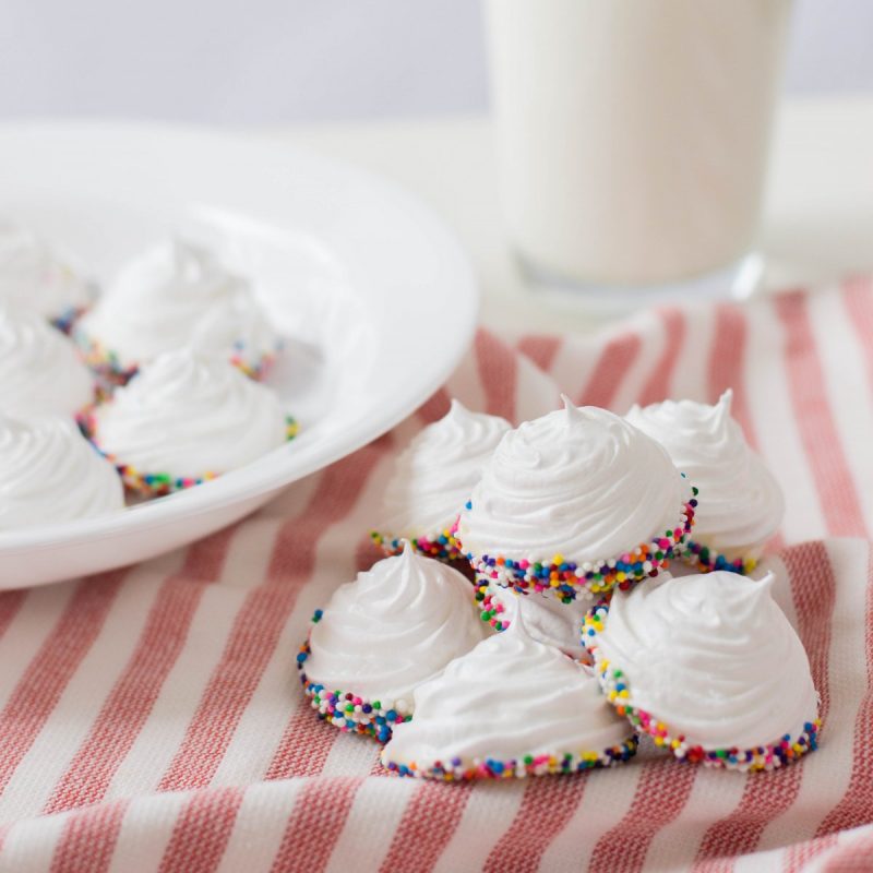 Get ready for a simple and easy birthday dessert idea that packs a ton of pizzaz with this birthday meringue cookies recipe! These beautiful white peaked meringues are dipped in white chocolate and covered in rainbow sprinkles for a fun and festive sweet birthday treat! This recipe uses just 5 ingredients and are just as cute as can be!