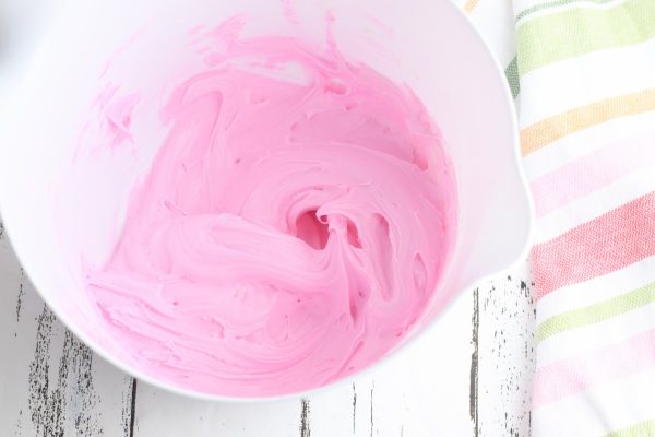 In a large bowl, combine the white icing and pink food coloring. Stir until the desired color is reached.