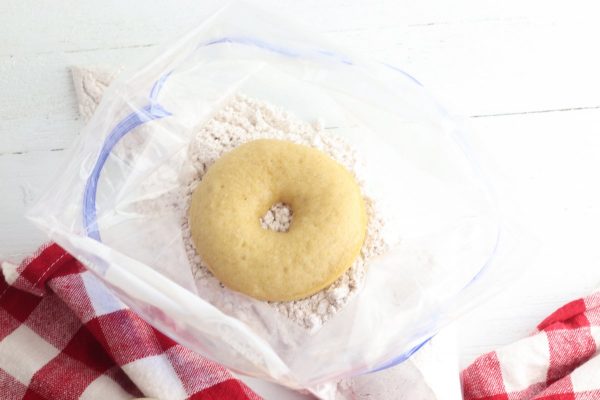 Place one or two donuts in the bag. Close the bag and shake to coat the donuts with sugar.