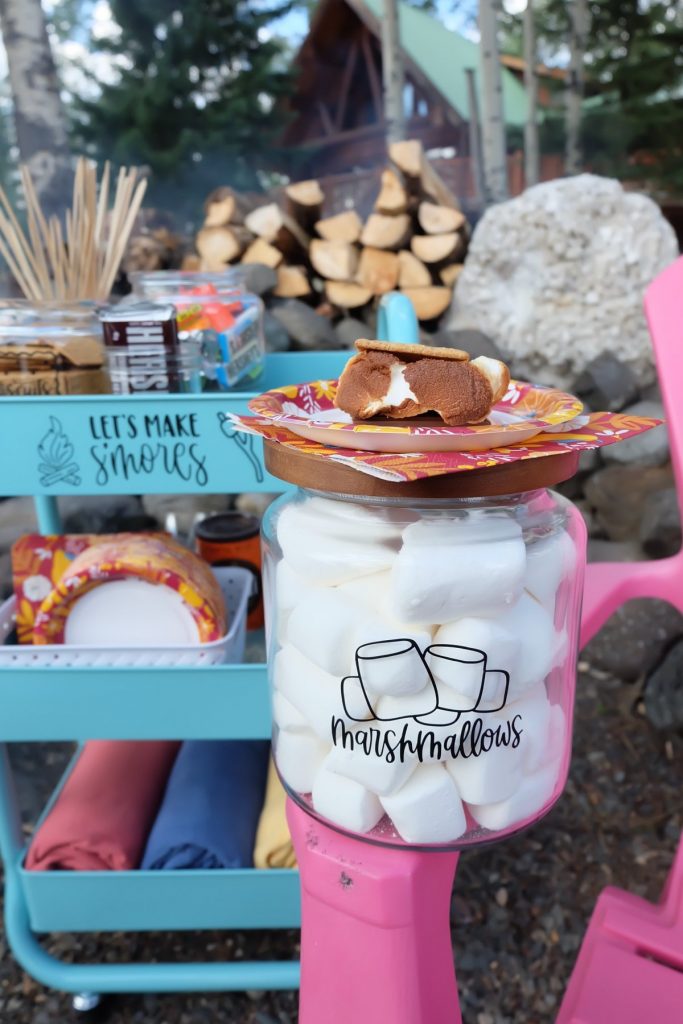 Adorable smores cart and smores supplies sitting in front of a beautiful cabin in BC
