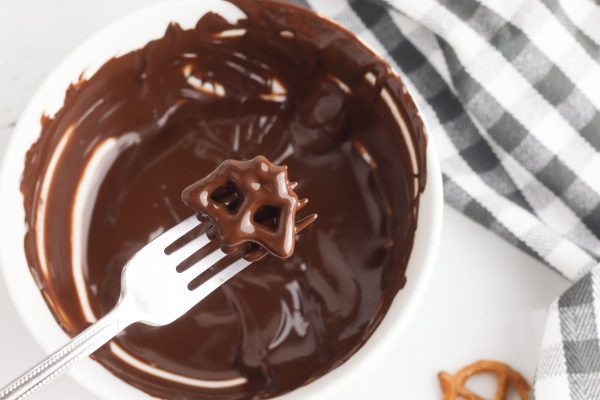 Place the bat pretzels in the chocolate one at a time, making sure both sides of the pretzel are coated. Remove the pretzel from the chocolate with a fork and tap the fork on the side of the bowl to remove the excess chocolate.