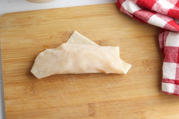 Roll the center of the egg roll up toward the top corner. Wet a finger and rub it on the top corner, then fold it over to seal.