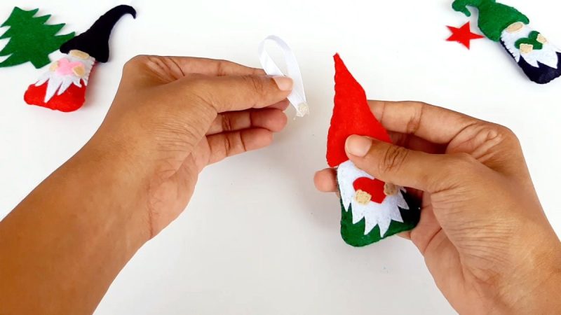 Fold a piece of ribbon, yarn or piece of twine in half and use a hot glue gun to glue the ends to the back of the gnome’s hat near the top. *You could also sew the loop into the top of the hat by simply placing it where you would like while sewing the front and back hat pieces together.