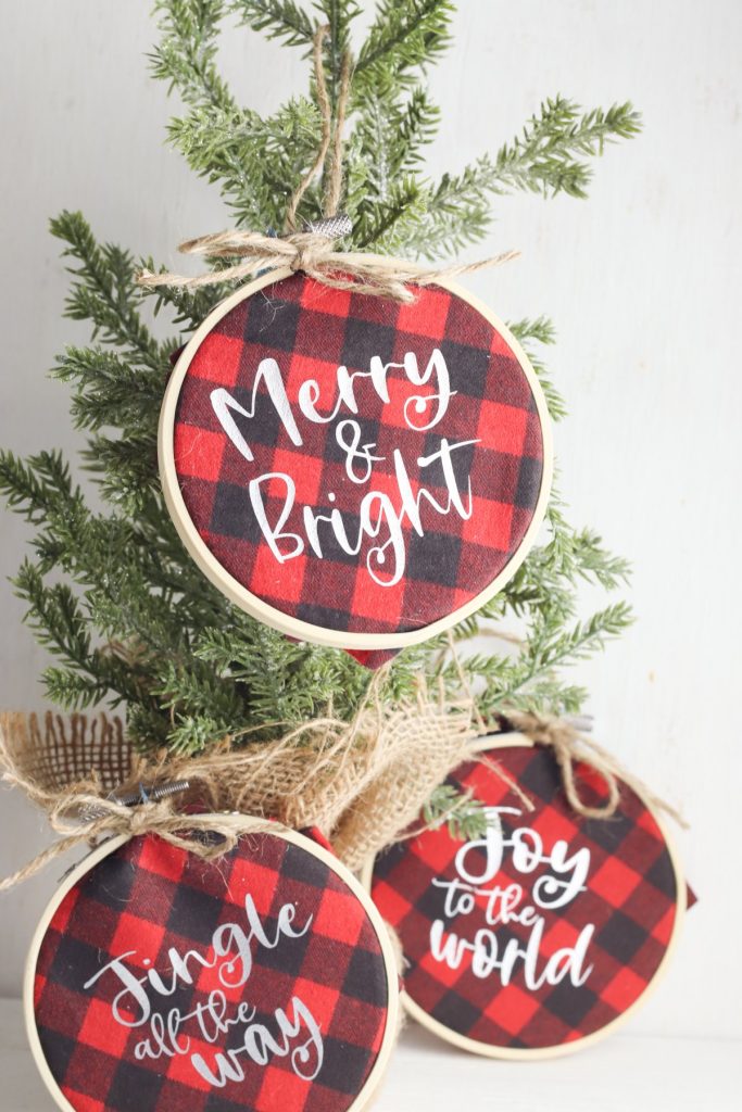 Learn how to make Buffalo plaid ornaments with the help of the Cricut Explore Air, Cricut Maker or Cricut Joy. These DIY Buffalo Plaid Christmas Ornaments combine mini embroidery hoops and HTV to make a quick and easy Christmas craft to decorate your Christmas tree! Includes three free Christmas SVGs!