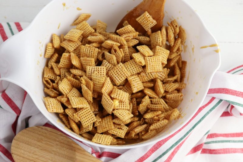 Remove the pan from heat and add the baking soda. Stir to mix the baking soda into the other ingredients, then immediately pour the mixture over the Chex and popcorn.