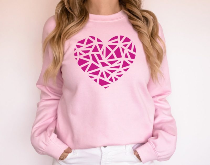 Woman Wearing Simple Geometric Heart Sweatshirt. The shirt is light pink and the heart is magenta. 