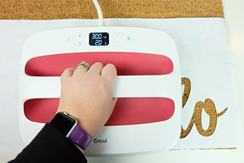 Heat your Cricut EasyPress to 300F. Carefully peel the freezer paper off of the cutting mat and lay it on top of the doormat in the area where you would like to stencil. Make sure you add the centers of your letters. Press the freezer paper to the doormat using your Cricut EasyPress, heating for approximately 30 second.