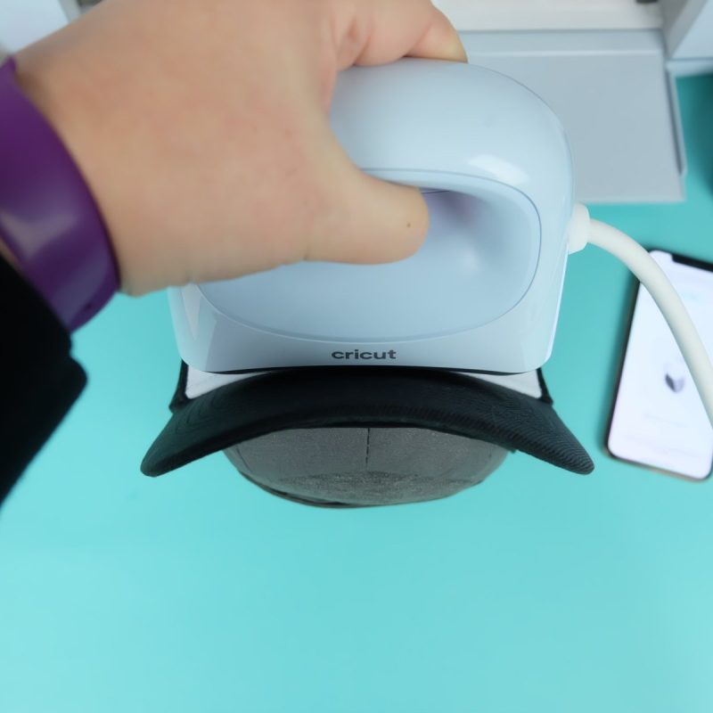 Cricut heat press pressing a Cricut hat.