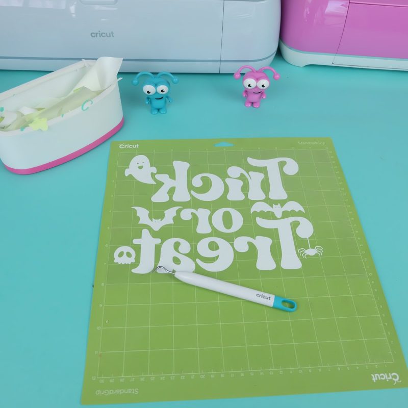 Once your machine is done cutting, unload your mat, remove the vinyl and weed away the excess vinyl surrounding your design. Don't forget inside the letters (e, a, and o's) as well as the ghosts, bats, spiders and skulls eyes and mouth.
