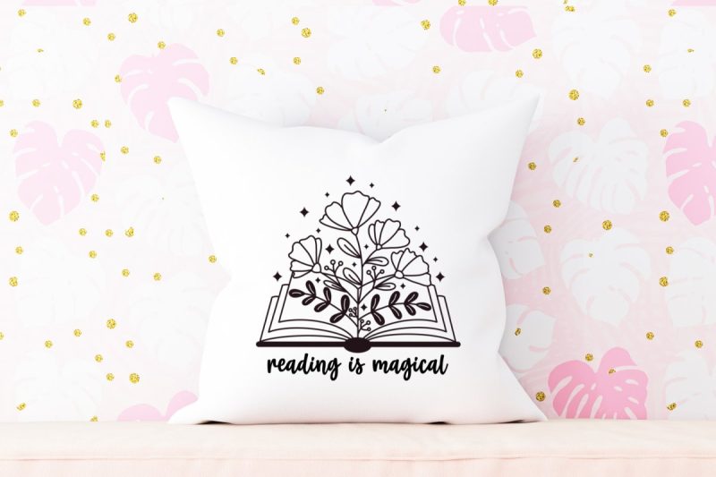 White throw pillow against pink monstera leaf wallpaper. Pillow has a book with wildflowers and the words reading is magical