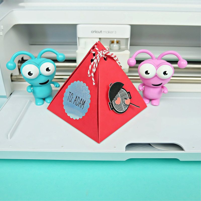 Pyramid Party Favor Box sitting in front of a Cricut Maker 3 with two Cricut cuties