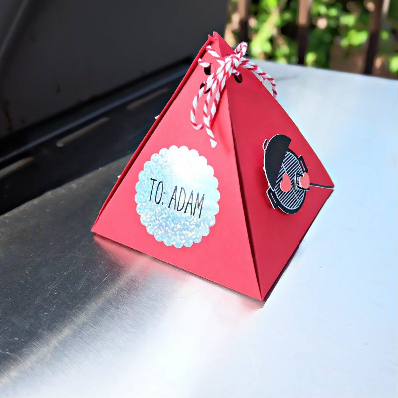 Cricut BBQ party favor pyramid box sitting next to a BBQ.