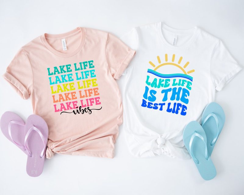 Pink shirt that says Lake Life Vibes on front in rainbow letters and white shirt that says Lake Life Is The Best Life. Shirts designed by Crystal Allen at Hello Creative Family. 