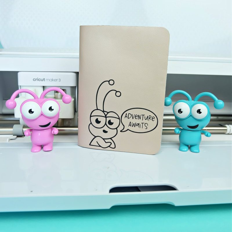 Cricut Maker 3 with a handmade passport holder with a Cricut Cutie on the front.