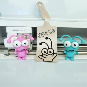 Cricut Maker 3 with a Cricut Luggage Tag and two Cricut Cuties.