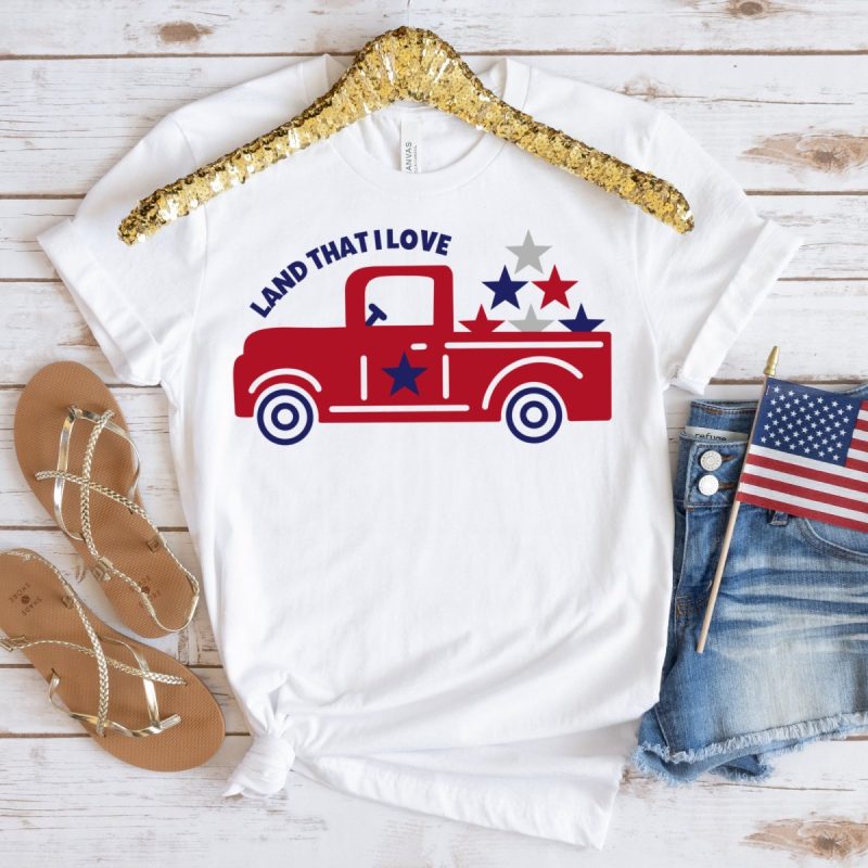 Shirt with adorable red vintage truck with the words Land That I Love above and red, white and blue stars in the trunk. SVG created by Crystal Allen from Hello Creative Family.