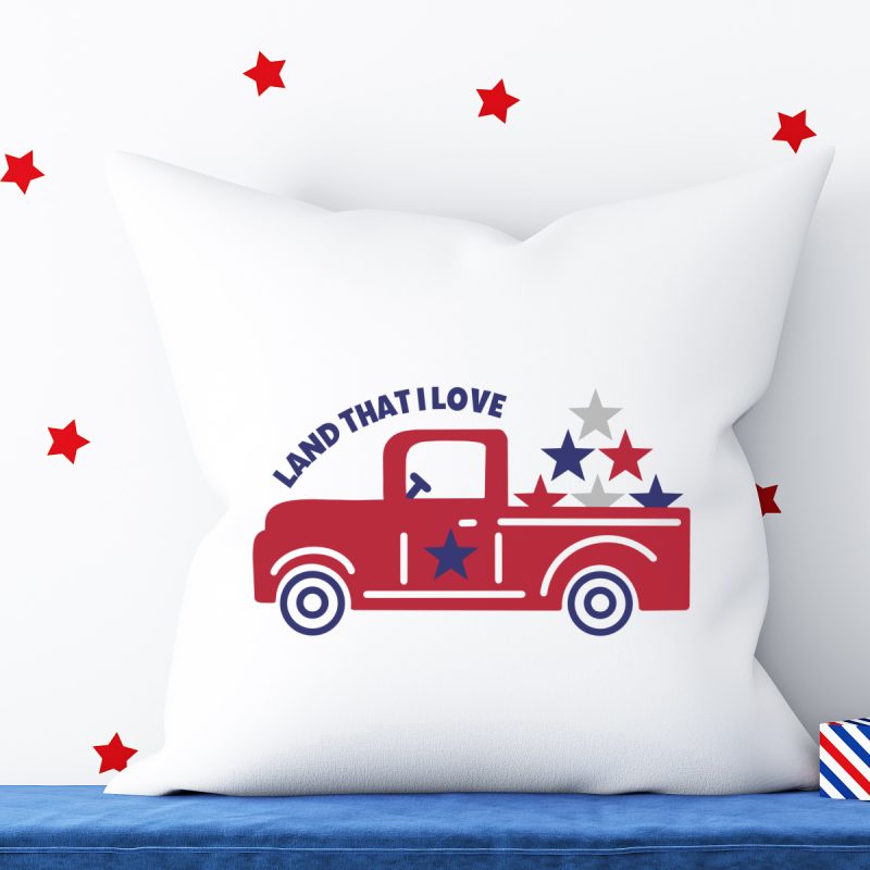 Pillow with adorable red vintage truck with the words Land That I Love above and red, white and blue stars in the trunk. SVG created by Crystal Allen from Hello Creative Family.