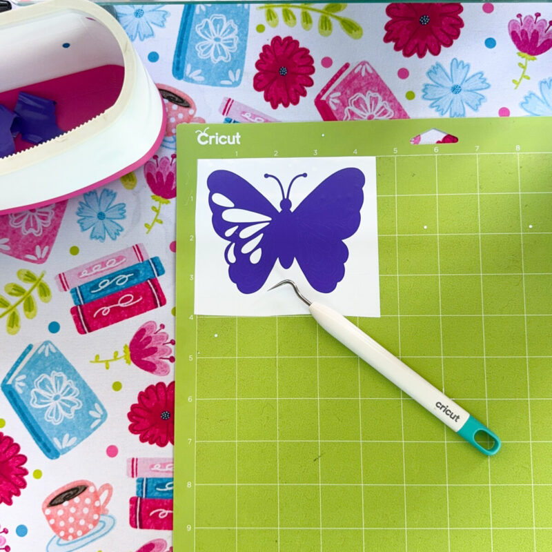 Vinyl being weeded on a Cricut cutting mat.