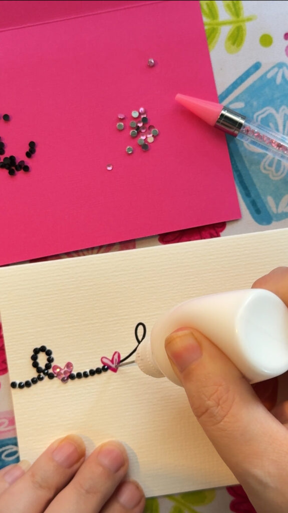 Precision glue bottle adding a thin layer of glue to the front of a card overtop vinyl