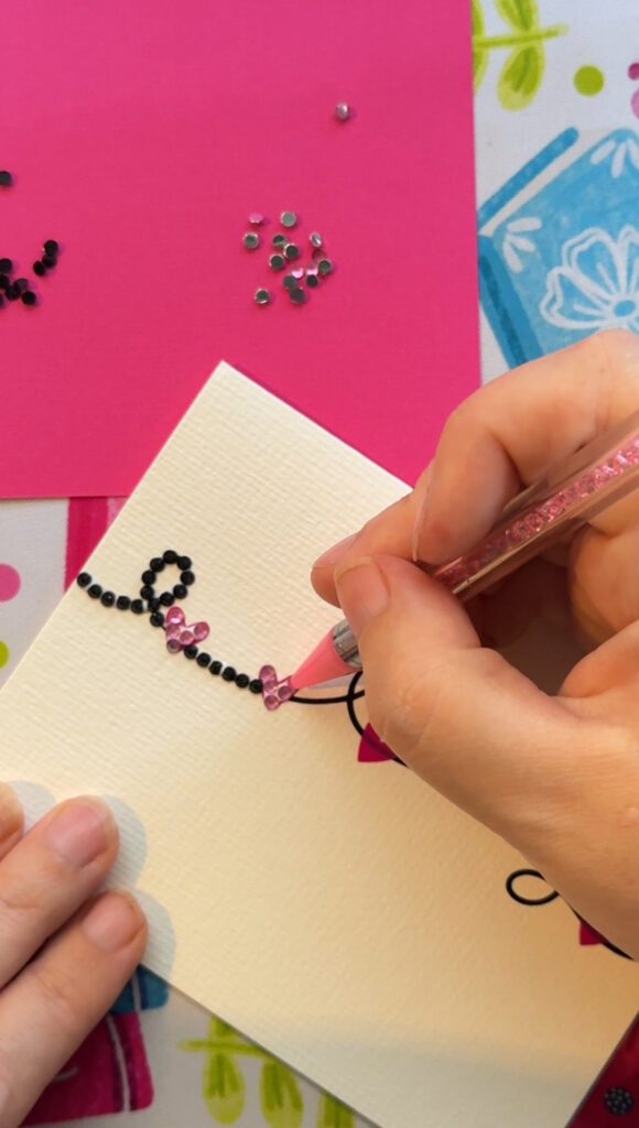 Dotting pen applying rhinestones to the front of a card