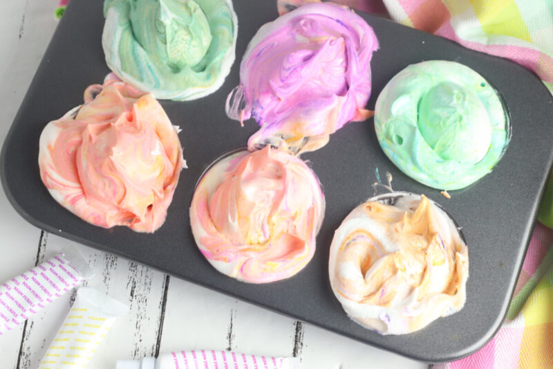 Eggs sitting in whipped cream colored with food coloring. 