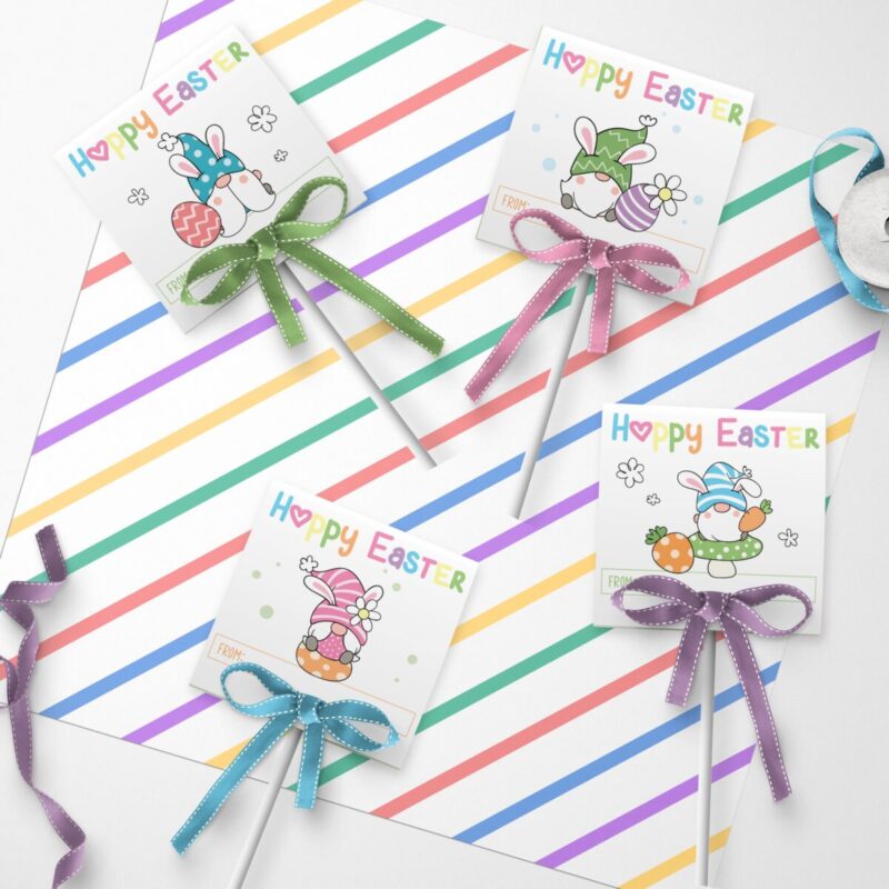 Adorable Easter Gnome Lollipop Covers with lollipops laying on top of piece of scrapbook paper with pastel stripes.