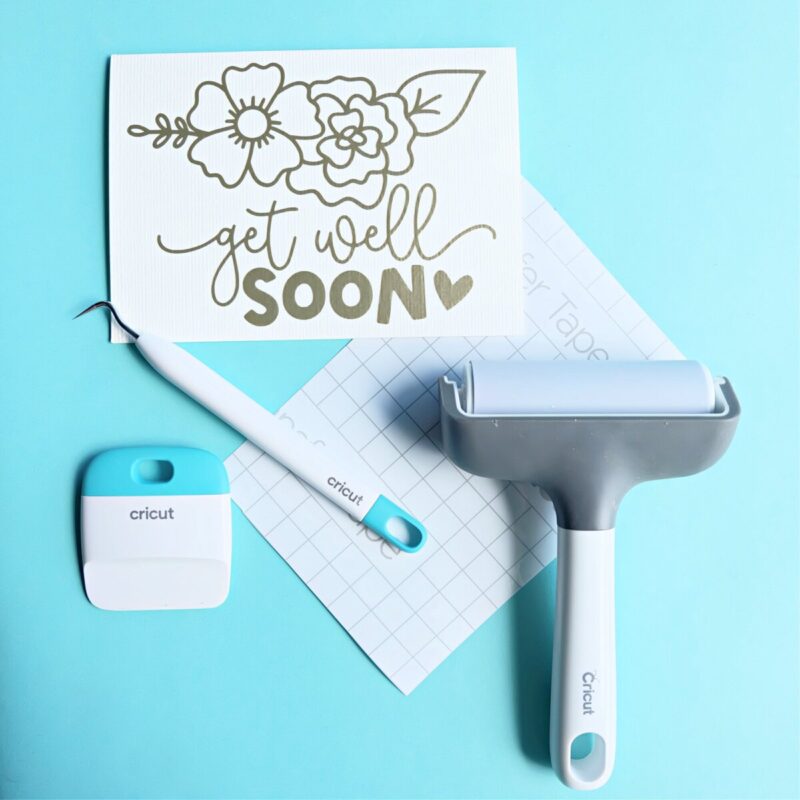 How To Reverse Weed Vinyl. Image of card with a vinyl design that says "Get Well Soon" with flowers. Around the card are Cricut Tools