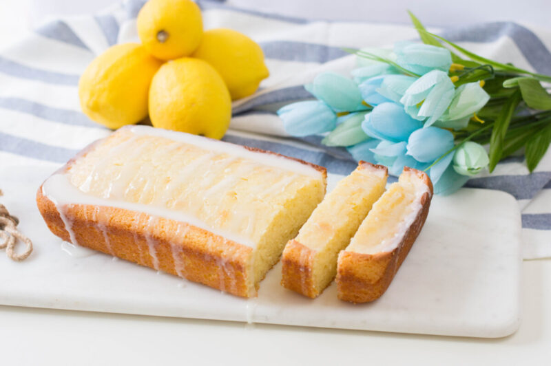 Glazed Lemon Loaf with lemons, tulips and a kitchen towel