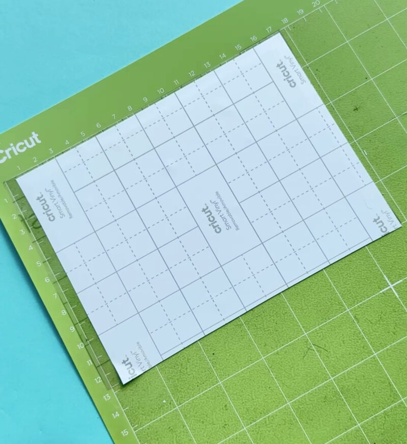 Cut a piece of transfer tape slightly larger than your design. Peel off the paper backing and place the transfer tape directly over the entire cut design. You will now have a sandwich with the vinyl backing on the bottom, the vinyl design in the middle and the transfer tape on top.