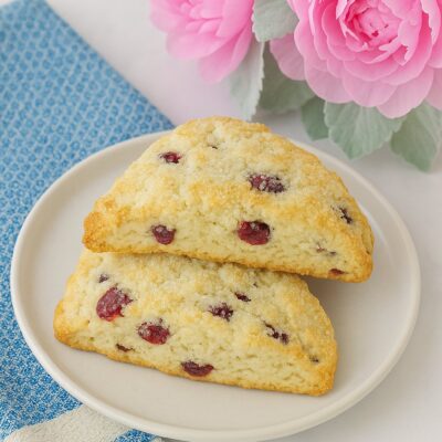 Two scones sitting on a white plate with a blue towel and pink flowers. 20 Minute Start To Finish Scone Recipe for Two... or One