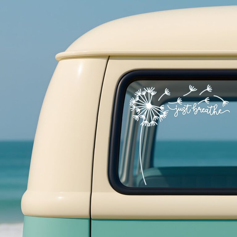 White “Just Breathe” dandelion car decal displayed on the rear side window of a vintage mint and cream van parked by the ocean, with blue sky and turquoise water in the background.