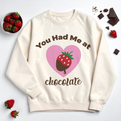 Cream sweatshirt mockup featuring a chocolate-dipped strawberry inside a heart with the phrase “You Had Me at Chocolate.”