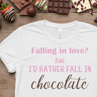 White t-shirt mockup with the phrase “Falling in love? Nah I’d rather fall in chocolate” surrounded by chocolate pieces.