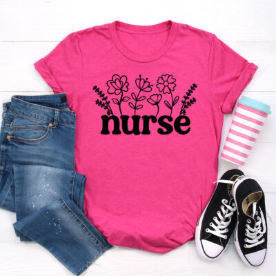 Hot pink t-shirt featuring a black floral nurse SVG design with flowers growing from bold lettering, styled with jeans, sneakers, and a striped coffee cup on a white background.